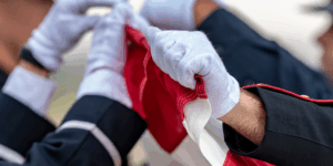 The gloved hands of two soldiers folding the American flag