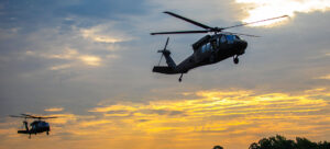 2 helicopters flying low in sunset sky