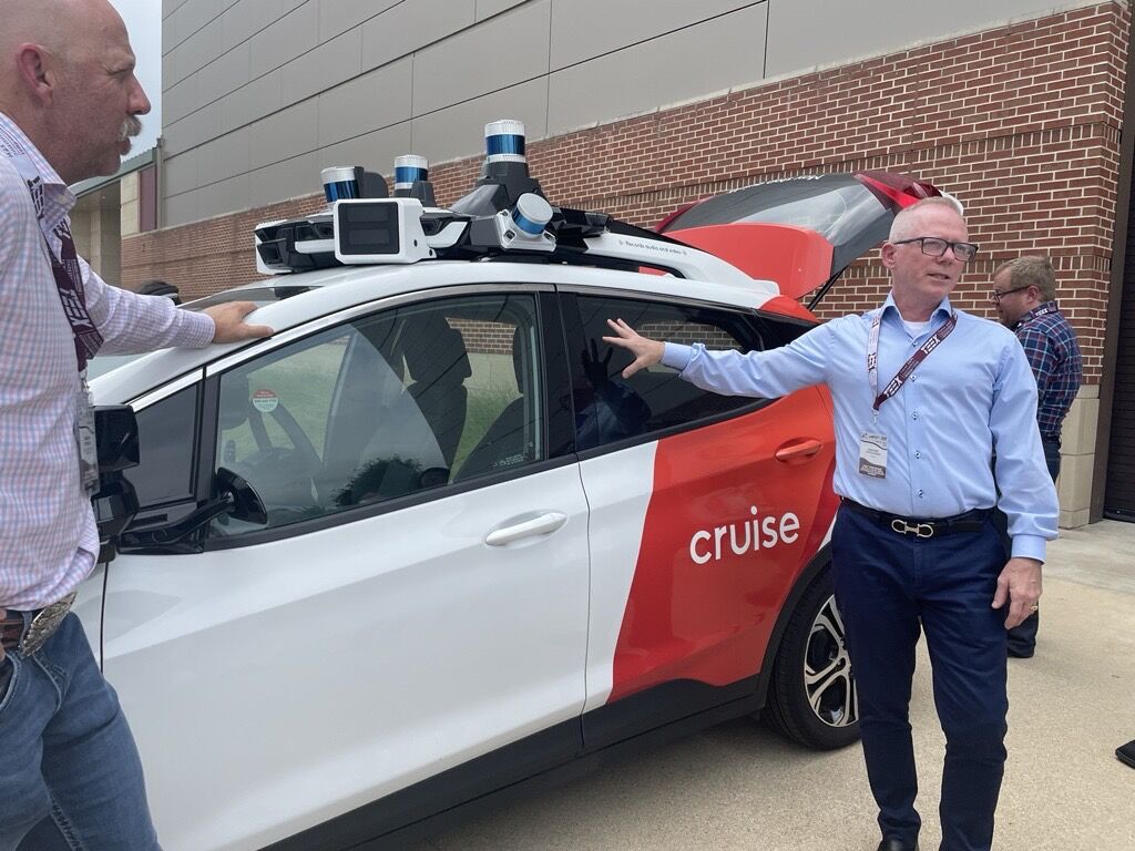 2 men standing by autonomous car at conference